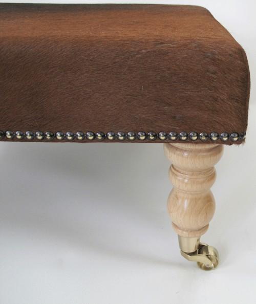 Brown cowhide footstool on castors 213